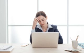 The image shows a woman, office worker suffering from a headache