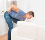 Picture of a man with back pain lifting a sofa