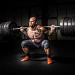 man doing a squat with barbells