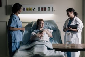 woman-cradles-newborn-baby-under-watchful-eyes-of-doctor