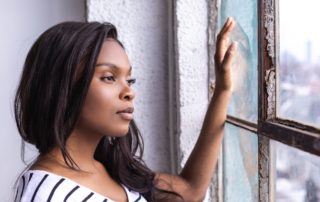 young woman gazes out of a rustic window