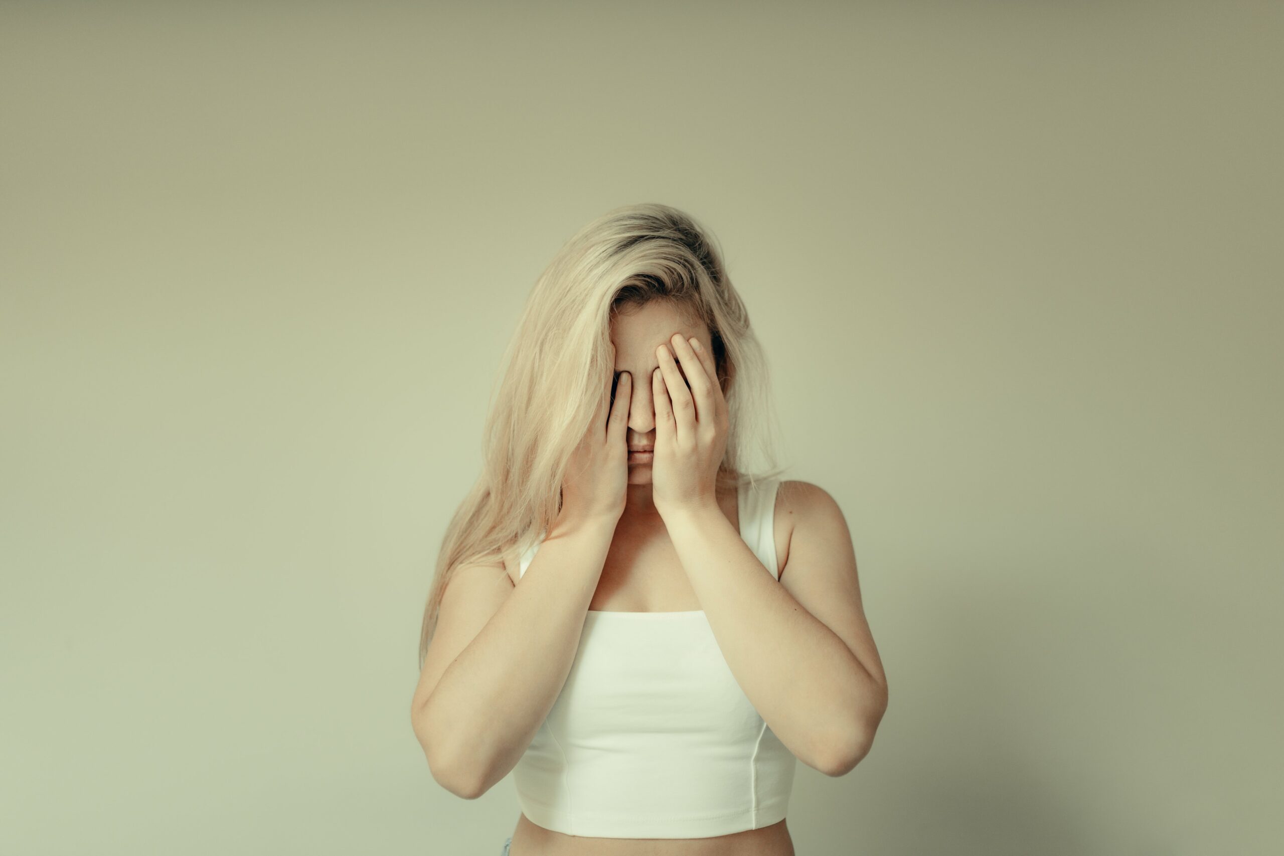 woman holds her hands to her face covering it scaled