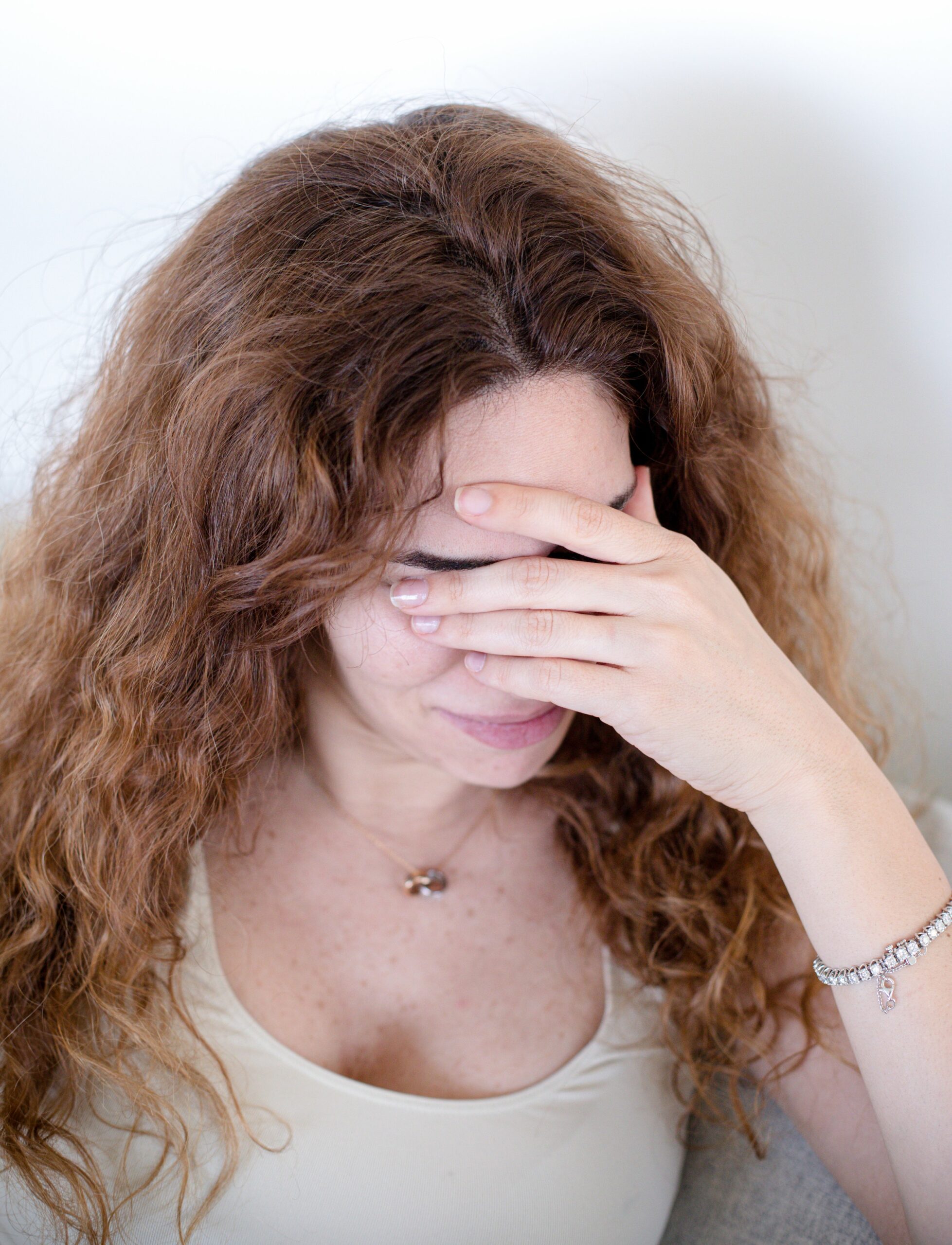 person holds one hand over their eyes scaled