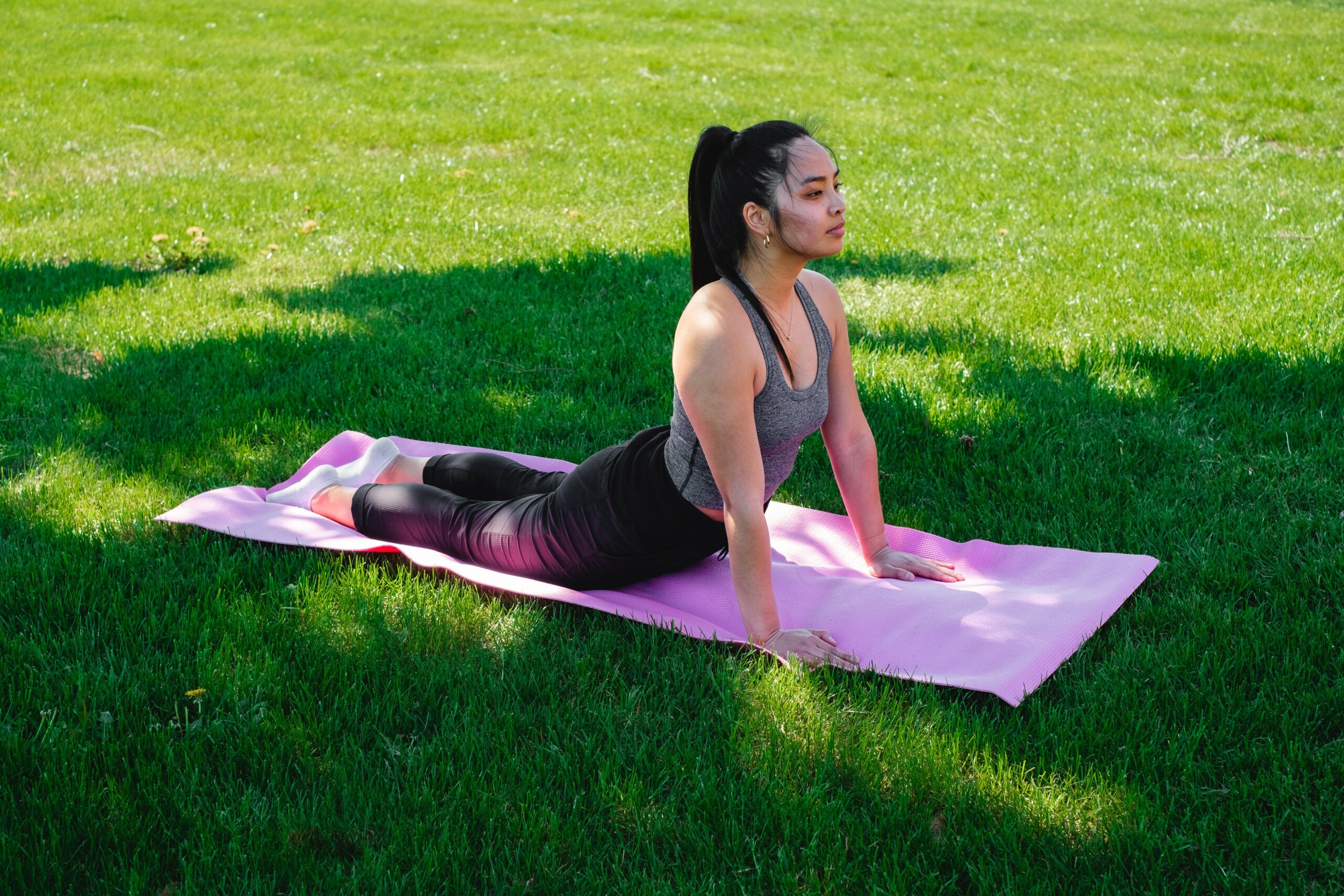 woman practices yoga in green grass scaled