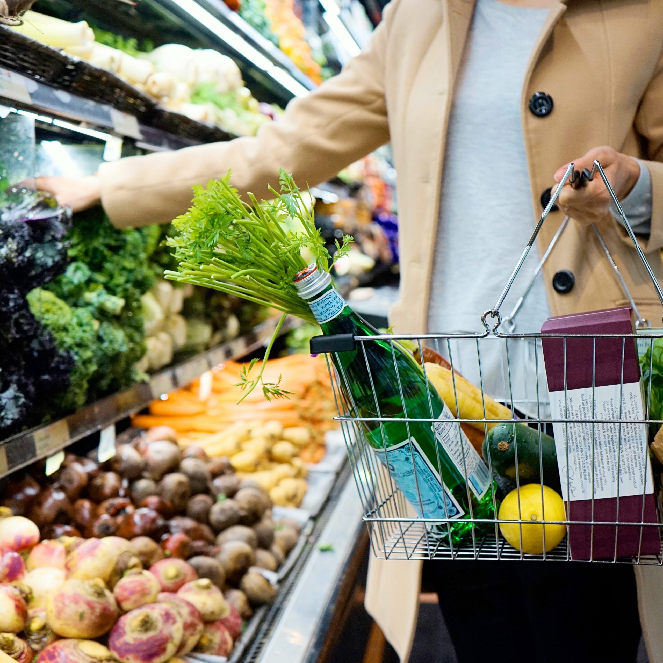 person uses a silver shopping basket to shop for groceries scaled