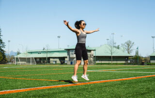 woman mid jumping jack floats above green grass