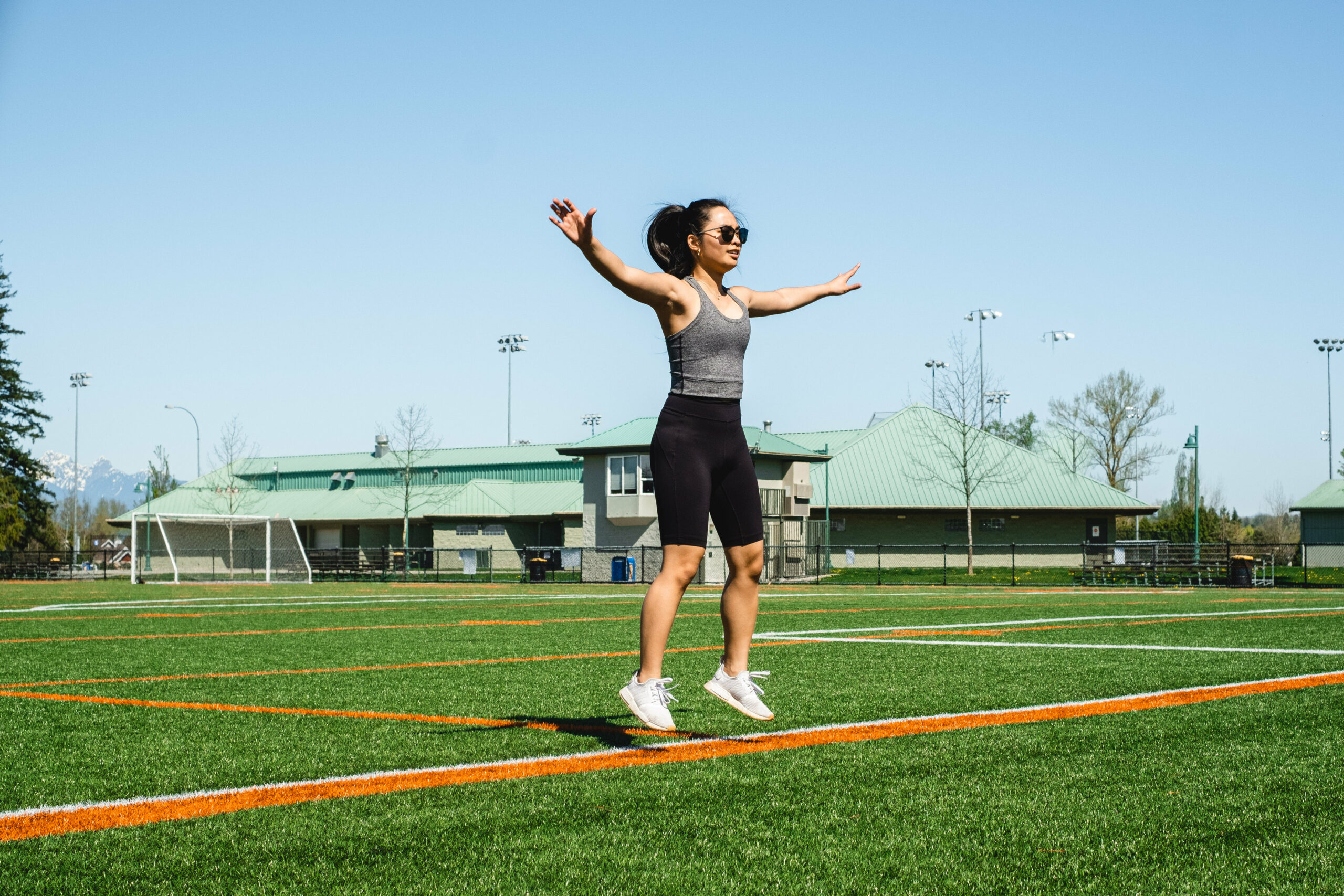 woman mid jumping jack floats above green grass scaled