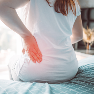 Woman sitting in her bed feeling backpain 
