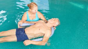 Senior man get hydrotherapy in a pool.