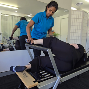 Physiotherapist guiding a postpartum woman through a gentle core exercise
